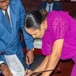 Benita Ebang Nzang, vestida de fucsia, firma un acta en la Sala Plenaria del Ministerio de Hacienda en Malabo durante su toma de posesión de 2024