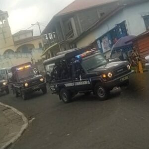 Columna de vehículos de la Gendarmería Nacional con las luces encendidas recorre una calle de Baney, al norte de la isla de Bioko